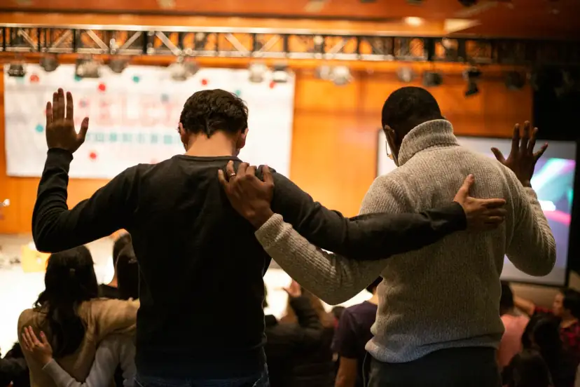 Two friends praying together, arms around each other's shoulders